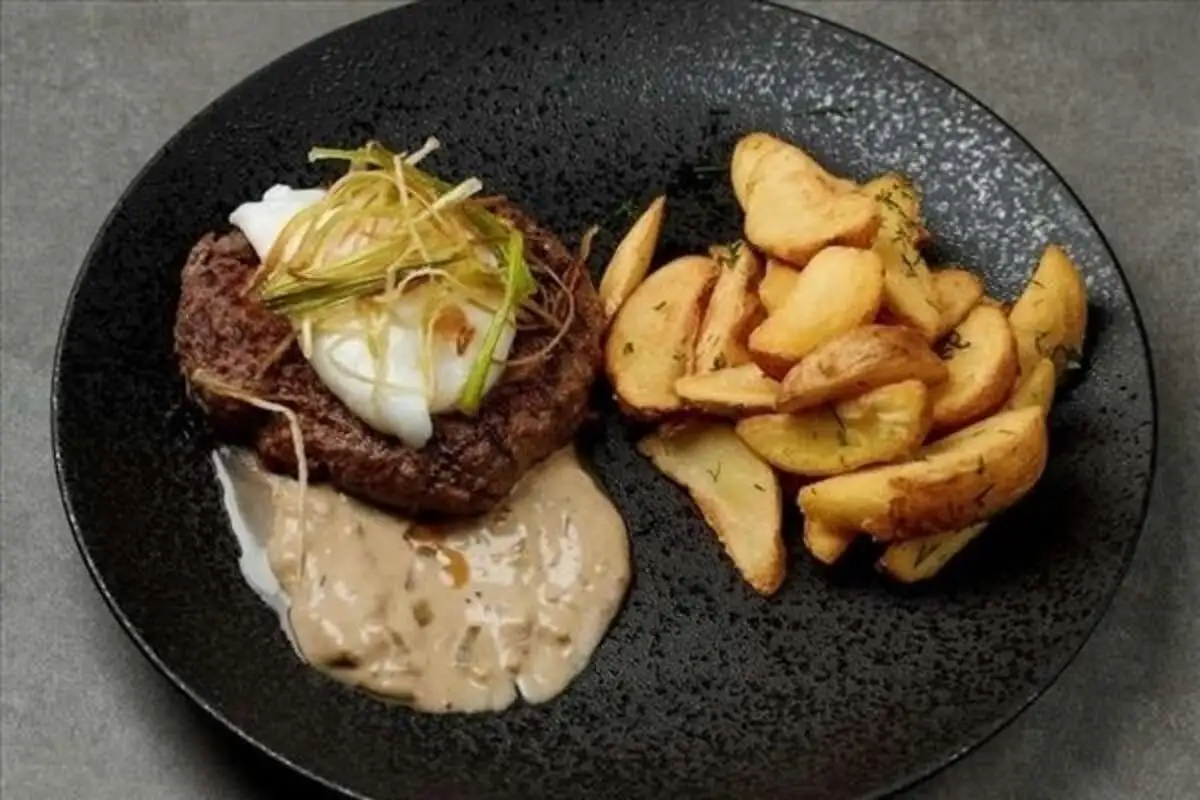 - Бифштекс из говядины с дольками картофеля, яйцом и грибным соусом
