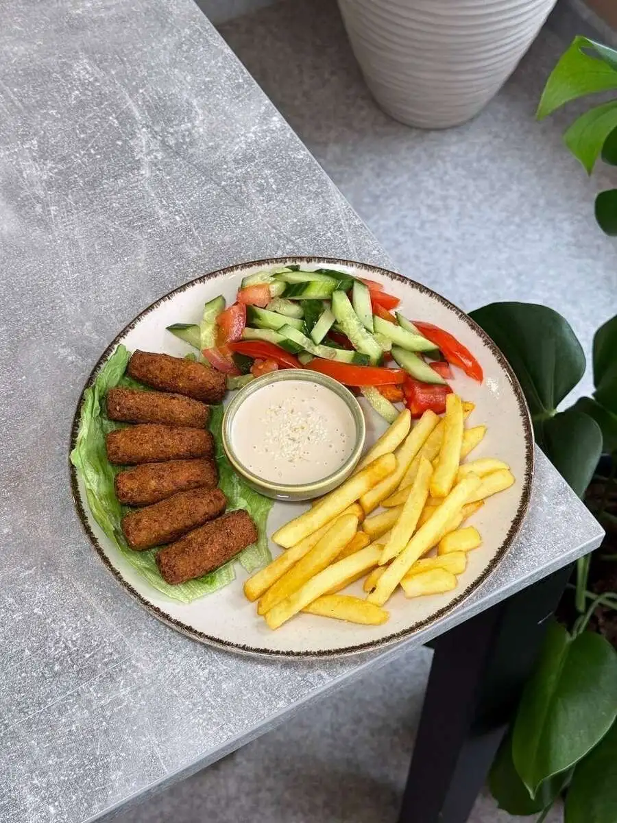 Фалафель с гарниром и ореховым соусом на тарелке